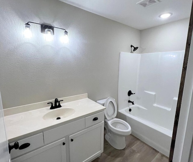 full bath featuring  shower combination, toilet, visible vents, wood finished floors, and vanity