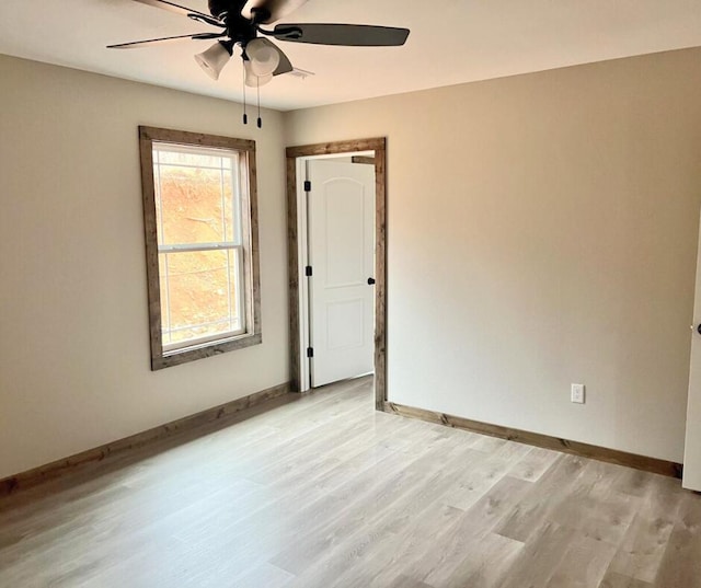 spare room with ceiling fan, baseboards, and light wood-style flooring