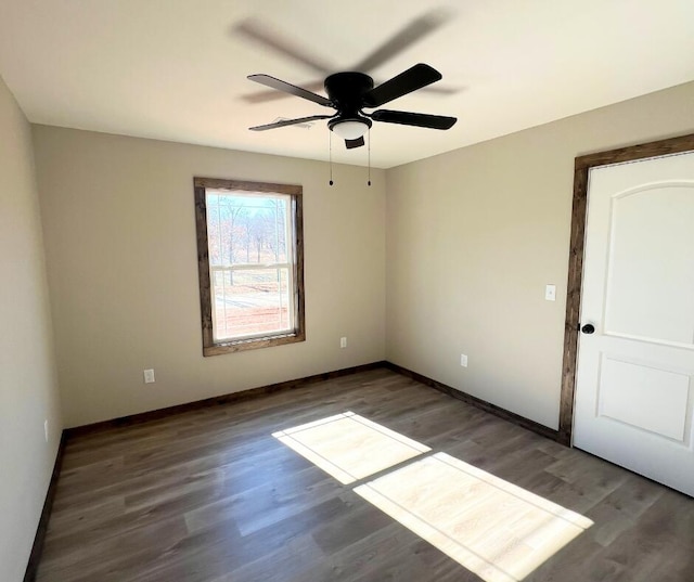 spare room with wood finished floors, a ceiling fan, and baseboards
