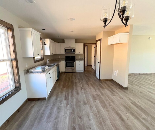 kitchen with light wood-style flooring, baseboards, stainless steel appliances, and a sink