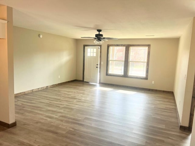 unfurnished living room with wood finished floors, baseboards, and ceiling fan