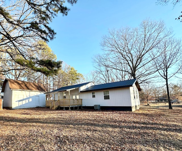 back of property featuring a storage shed, a deck, central AC, and an outbuilding