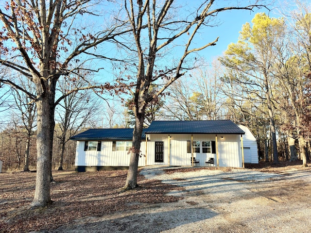 view of front of house featuring an outbuilding, metal roof, and dirt driveway