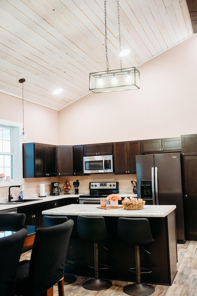 kitchen with a breakfast bar area, stainless steel appliances, light countertops, and decorative light fixtures