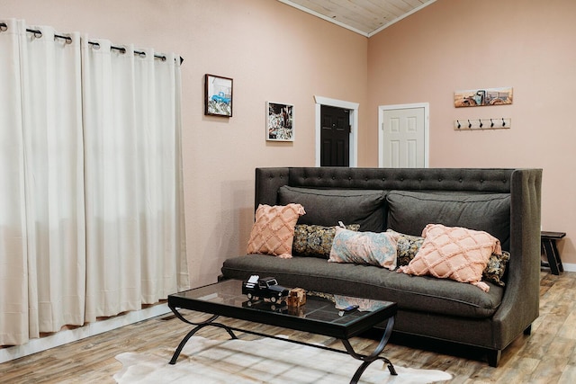 living area featuring lofted ceiling, light wood-style flooring, and crown molding