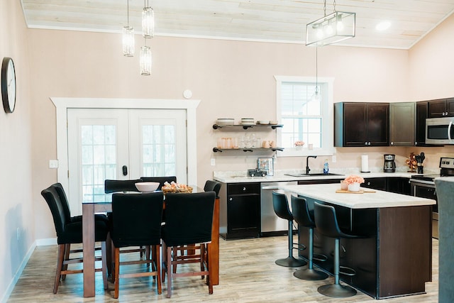 kitchen with dark brown cabinetry, a sink, a kitchen island, appliances with stainless steel finishes, and pendant lighting