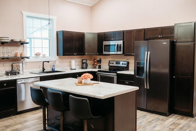 kitchen with appliances with stainless steel finishes, a center island, a sink, and dark brown cabinets