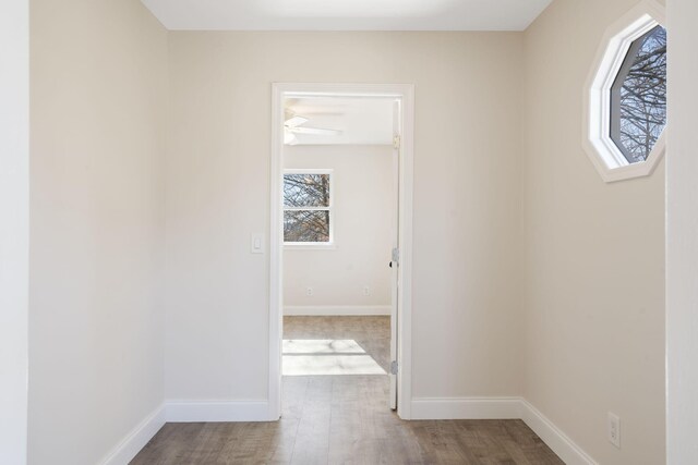 hall with baseboards and wood finished floors