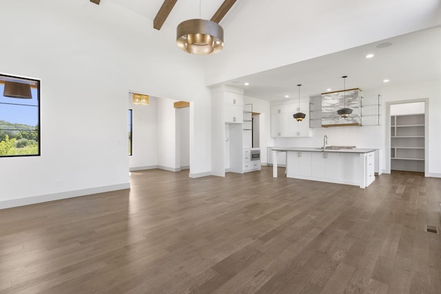 unfurnished living room with sink, beamed ceiling, dark wood-type flooring, and high vaulted ceiling