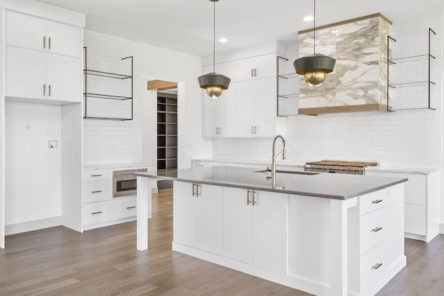 kitchen featuring pendant lighting, white cabinetry, and an island with sink