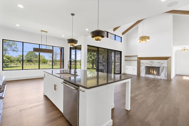 kitchen with an island with sink, white cabinetry, hanging light fixtures, and sink