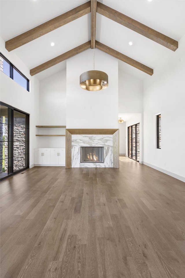 unfurnished living room with a high end fireplace, high vaulted ceiling, plenty of natural light, and dark wood-type flooring