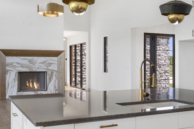 kitchen featuring white cabinets, dark stone countertops, sink, and a high end fireplace