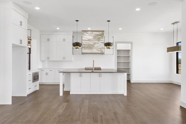 kitchen featuring light hardwood / wood-style floors, white cabinetry, hanging light fixtures, and a kitchen island with sink