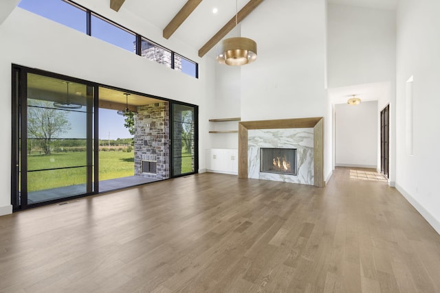 unfurnished living room with beamed ceiling, hardwood / wood-style flooring, a fireplace, and high vaulted ceiling