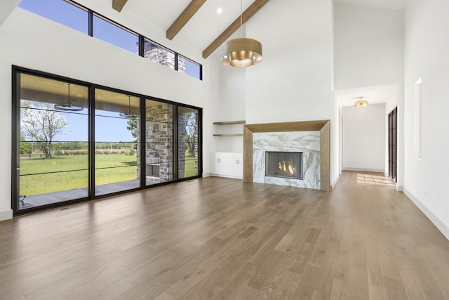 unfurnished living room with beam ceiling, a fireplace, high vaulted ceiling, and hardwood / wood-style floors