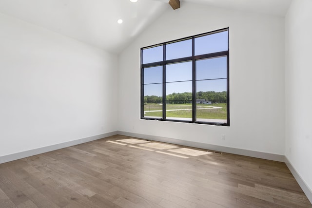 unfurnished room with vaulted ceiling with beams, light hardwood / wood-style floors, and ceiling fan