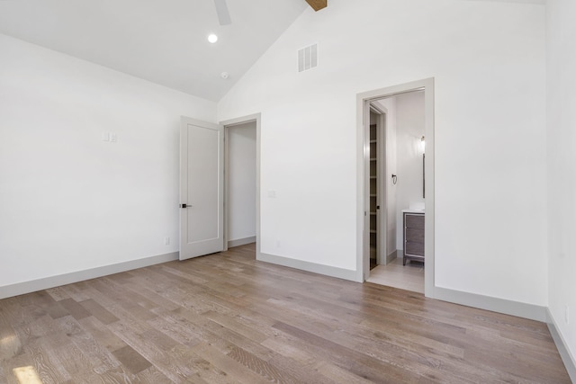 unfurnished bedroom with ceiling fan, light wood-type flooring, high vaulted ceiling, and ensuite bath