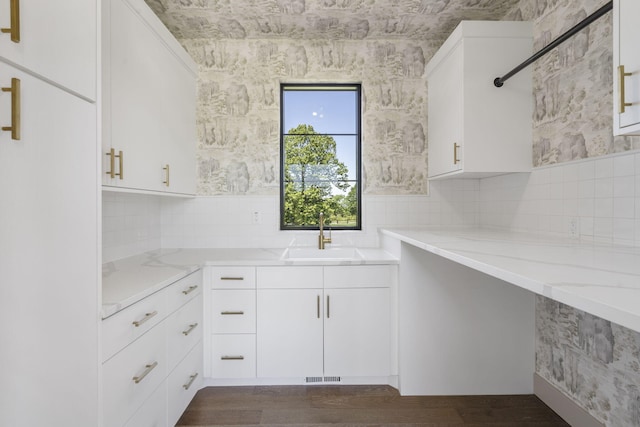 kitchen featuring backsplash, dark wood-type flooring, white cabinets, sink, and light stone countertops