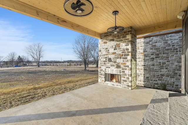 view of patio with an outdoor stone fireplace and a rural view