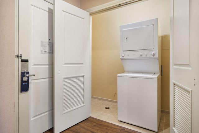 clothes washing area featuring stacked washer and clothes dryer and hardwood / wood-style flooring