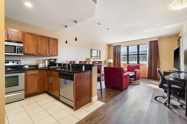 kitchen featuring kitchen peninsula, sink, stainless steel appliances, and light wood-type flooring