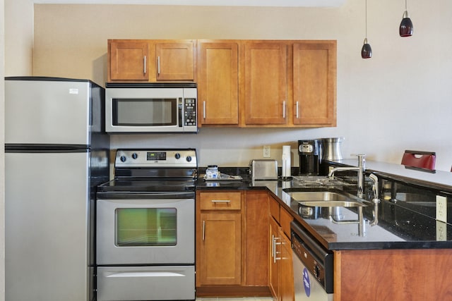 kitchen with dark stone counters, decorative light fixtures, appliances with stainless steel finishes, and sink