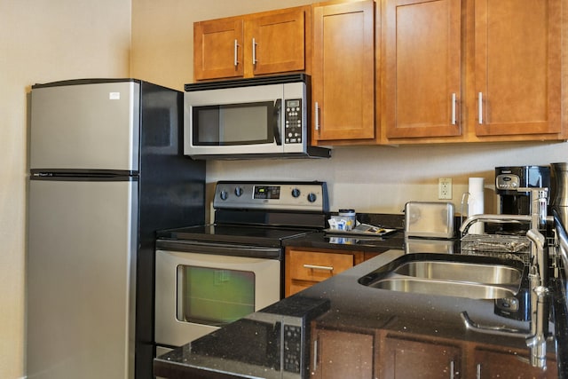 kitchen featuring dark stone counters, sink, and stainless steel appliances