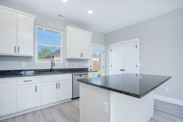 kitchen with a kitchen island, stainless steel dishwasher, sink, light hardwood / wood-style floors, and white cabinetry