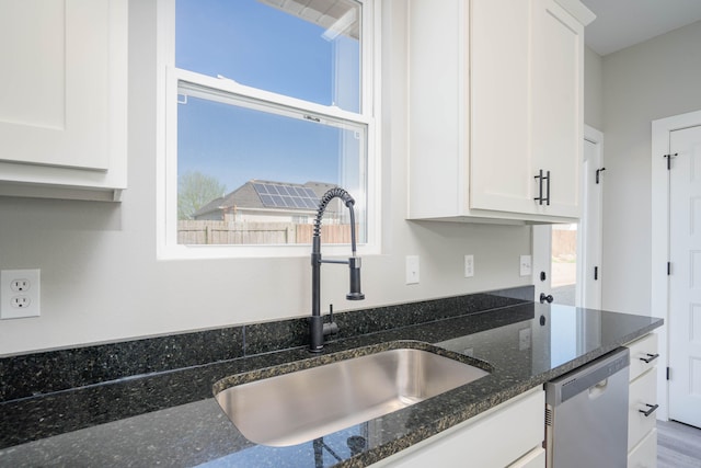 kitchen featuring dishwasher, dark stone counters, sink, and a wealth of natural light