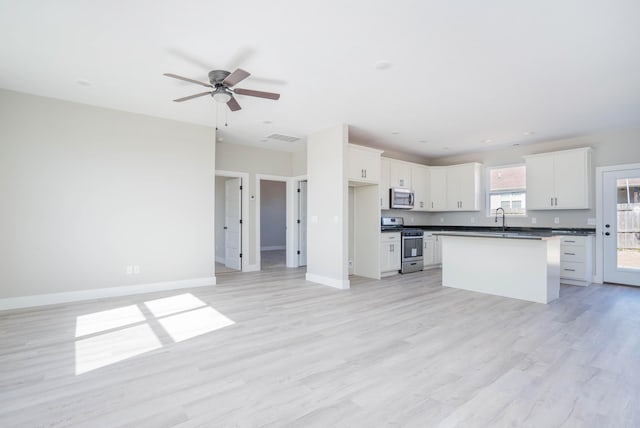 kitchen featuring light hardwood / wood-style flooring, appliances with stainless steel finishes, a kitchen island, and white cabinetry