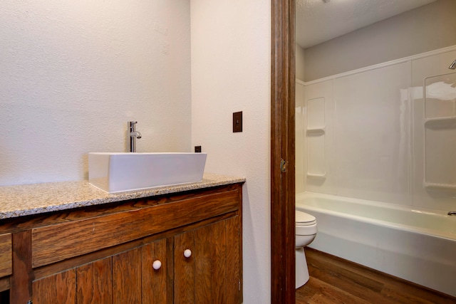 full bathroom featuring bathtub / shower combination, hardwood / wood-style floors, a textured ceiling, toilet, and vanity