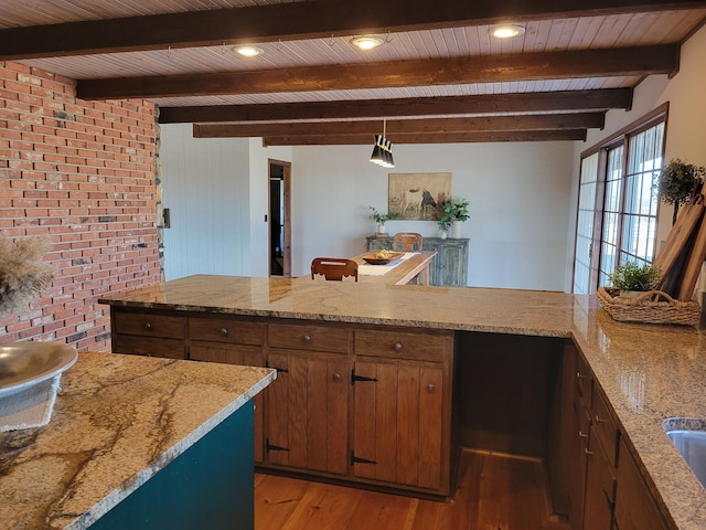 kitchen featuring beam ceiling, light hardwood / wood-style flooring, hanging light fixtures, and wooden ceiling