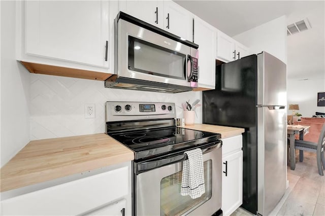 kitchen with white cabinets, appliances with stainless steel finishes, light hardwood / wood-style floors, and wooden counters