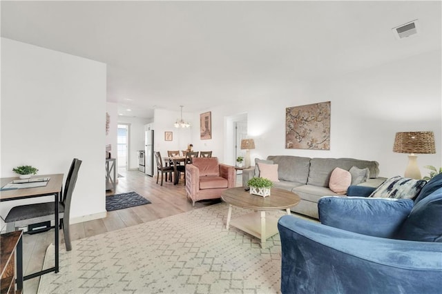 living room with a notable chandelier and light hardwood / wood-style flooring