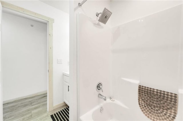 bathroom with wood-type flooring, vanity, and washtub / shower combination