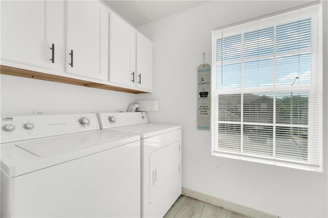 laundry area featuring washing machine and dryer, light hardwood / wood-style floors, and cabinets