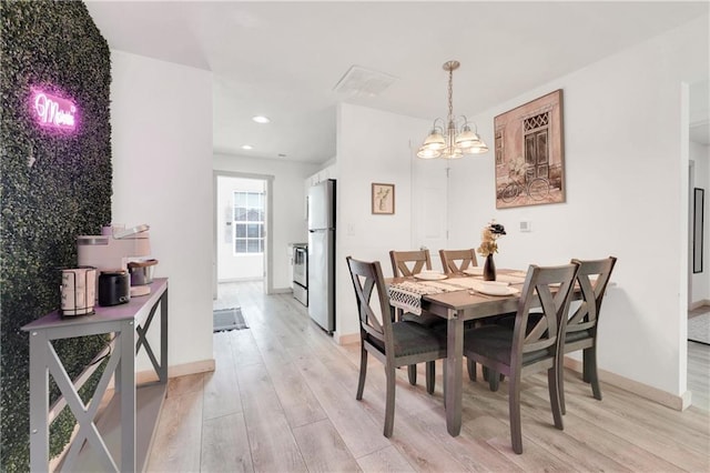 dining space with an inviting chandelier and light hardwood / wood-style floors