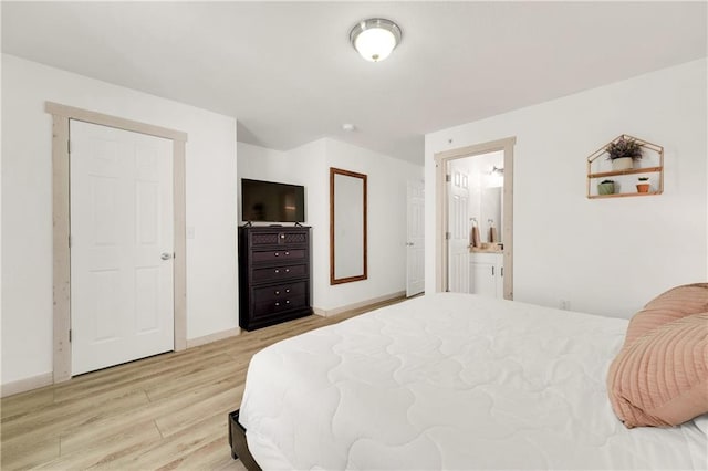 bedroom with ensuite bathroom and light hardwood / wood-style flooring