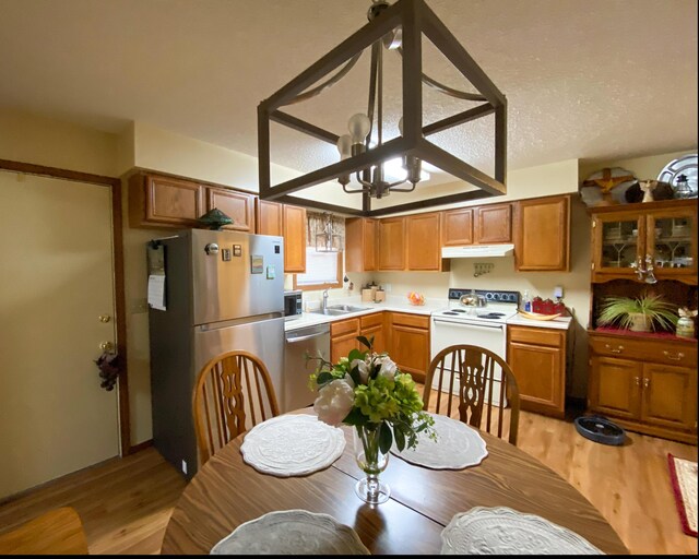 kitchen featuring brown cabinets, light wood finished floors, light countertops, a sink, and appliances with stainless steel finishes