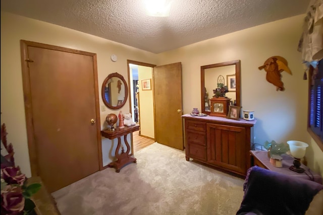 hallway with light carpet and a textured ceiling