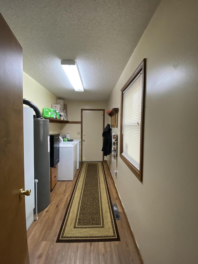 clothes washing area featuring light wood finished floors, laundry area, visible vents, washing machine and dryer, and a textured ceiling