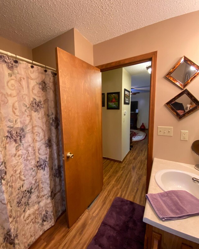 full bathroom featuring wood finished floors, a textured ceiling, and vanity