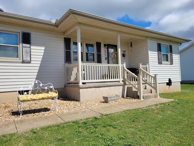 doorway to property with covered porch and a yard