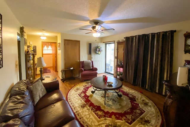 living room with a ceiling fan, wood finished floors, and a textured ceiling