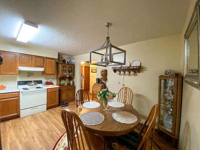 dining room with light wood-style flooring, a textured ceiling, and a notable chandelier