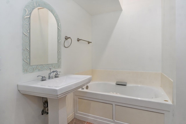 bathroom with a tub to relax in, tile patterned flooring, and sink