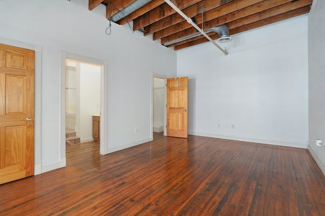 interior space with beamed ceiling, dark hardwood / wood-style flooring, and a high ceiling