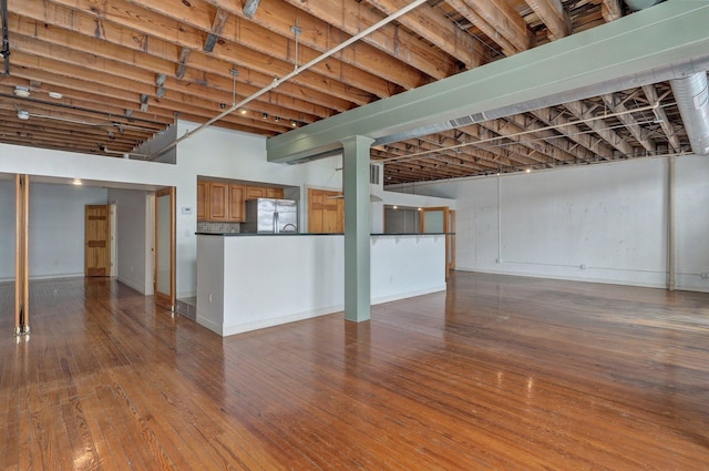 basement featuring stainless steel fridge and wood-type flooring