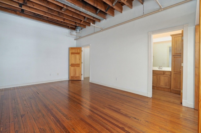 spare room with a high ceiling, sink, beam ceiling, and hardwood / wood-style floors